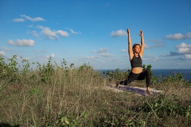 Junge Frau, die Yoga im Freien mit erstaunlicher Rückansicht tut. Bali. Indonesien.