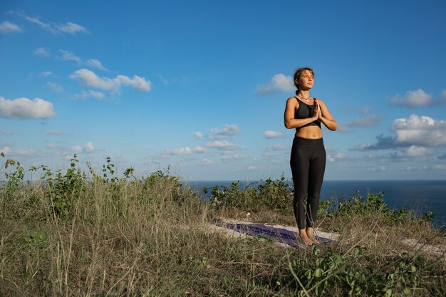 Junge Frau, die Yoga im Freien mit erstaunlicher Rückansicht tut. Bali. Indonesien.