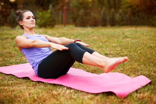 Junge Frau, die Yoga im Park tut. Gutes Dehnen hilft bei der Vermeidung von Muskelkater