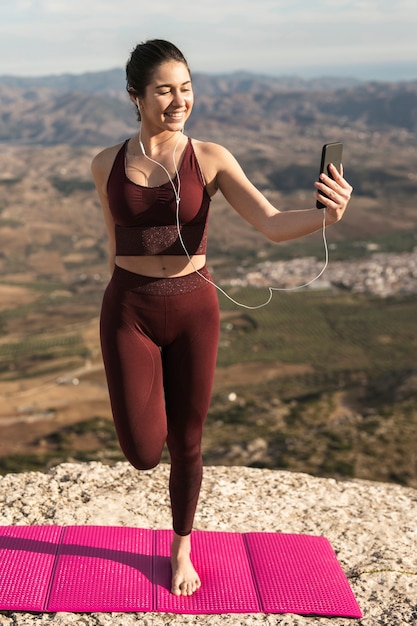 Junge Frau, die Yoga tut und Telefon verwendet