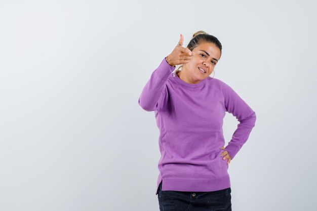 Junge Frau, die zeigt, während sie die Hand an der Taille hält