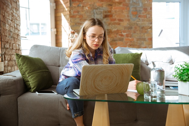 Junge Frau, die zu Hause während Online-Kursen oder kostenlosen Informationen selbst studiert