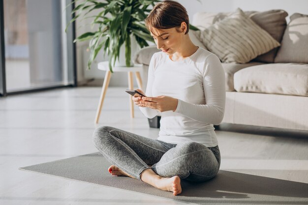 Junge Frau, die zu Hause Yoga auf Matte praktiziert