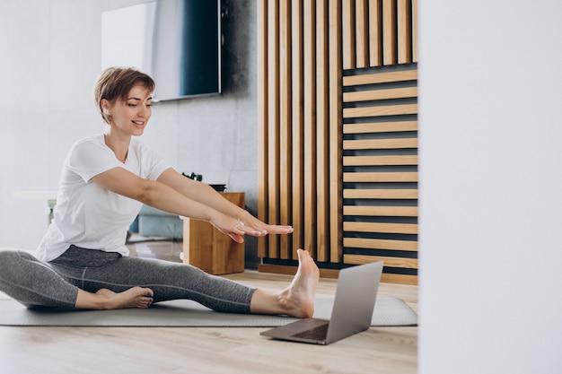 Kostenloses Foto junge frau, die zu hause yoga auf matte praktiziert