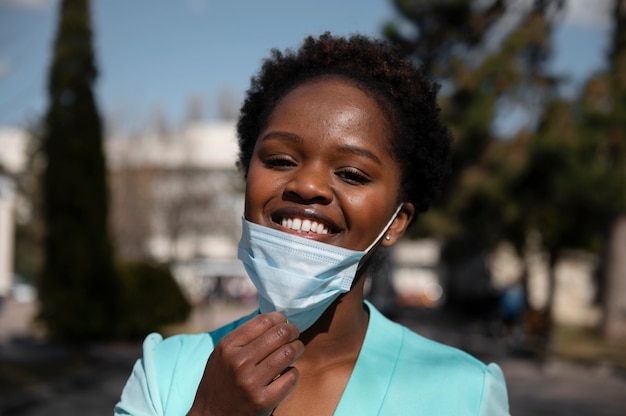 Junge Frau feiert die Aufhebung der Gesichtsmaskenbeschränkungen im Freien in der Stadt