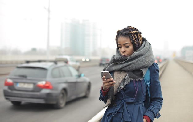 Junge frau geht die straße entlang und liest von einem smartphone