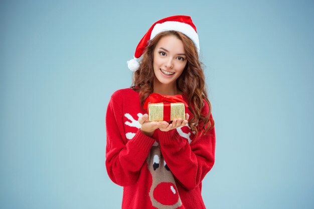 Junge Frau gekleidet in Weihnachtsmütze mit einem Weihnachtsgeschenk