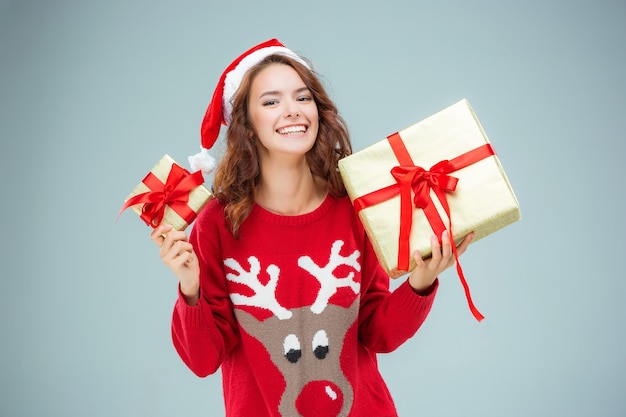 Junge Frau gekleidet in Weihnachtsmütze mit Weihnachtsgeschenken