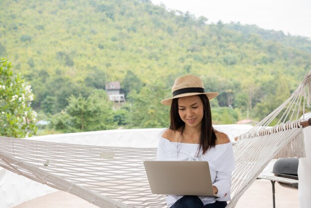 Junge Frau genießt einen Laptop in einer Hängematte am Strand