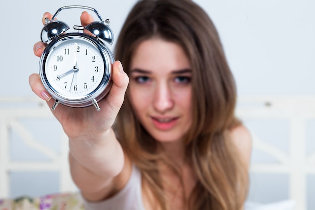 Junge Frau im Bett mit Wecker