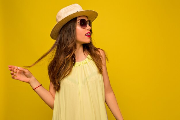 Junge Frau im gelben Kleid mit Hut und Sonnenbrille