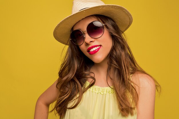 Junge Frau im gelben Kleid mit Hut und Sonnenbrille