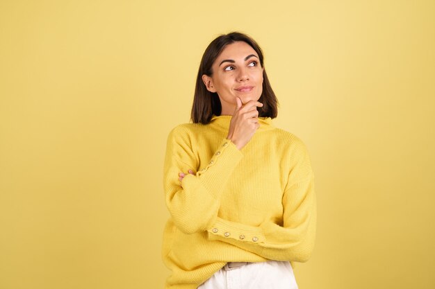 Junge Frau im gelben warmen Pullover, der ihr Kinn berührt