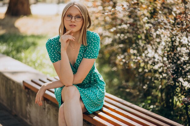 Junge Frau im grünen Kleid, das im Park sitzt