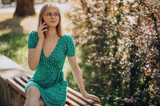 Junge Frau im grünen Kleid, das im Park sitzt