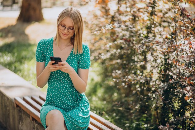 Junge Frau im grünen Kleid, das im Park sitzt