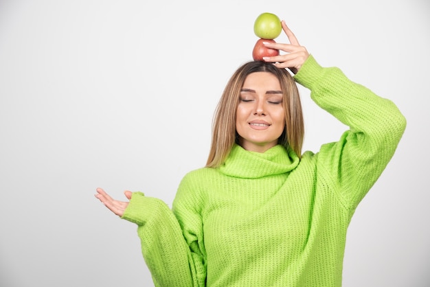 Junge Frau im grünen T-Shirt, das zwei Äpfel über Kopf hält