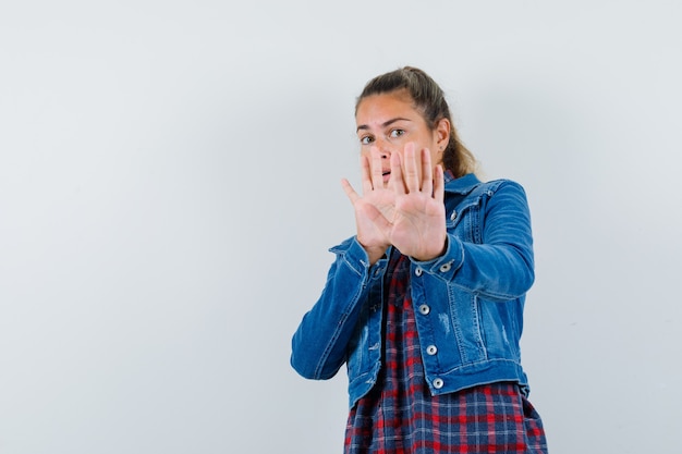 Junge Frau im Hemd, Jacke, die Stoppgeste zeigt und aufgeregt, Vorderansicht schaut.