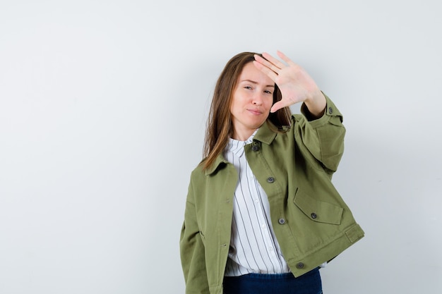 Junge Frau im Hemd, Jacke, die Stoppgeste zeigt und selbstbewusst aussieht, Vorderansicht.