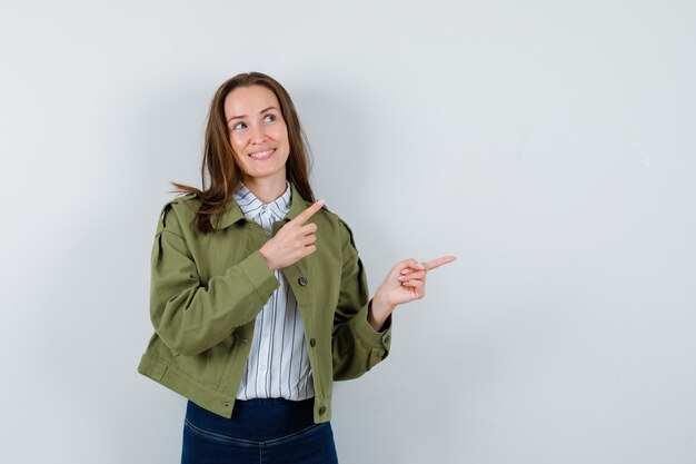 Junge Frau im Hemd, Jacke zeigt nach rechts und sieht verträumt aus, Vorderansicht.