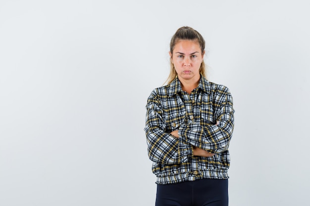 Junge Frau im Hemd, Shorts, die mit verschränkten Armen stehen und ernst schauen, Vorderansicht.