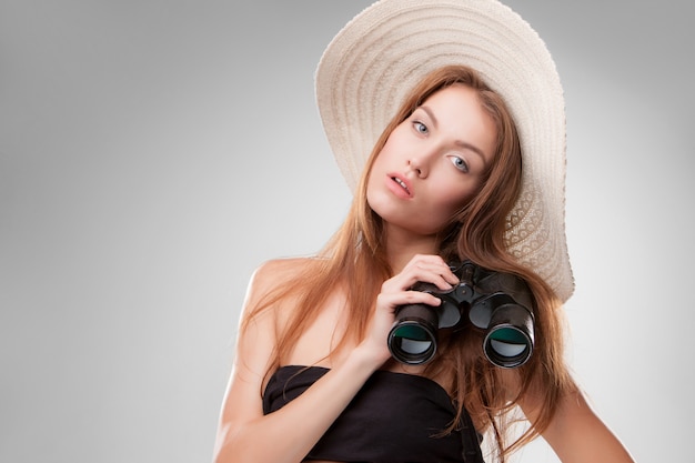 Junge frau im hut mit fernglas