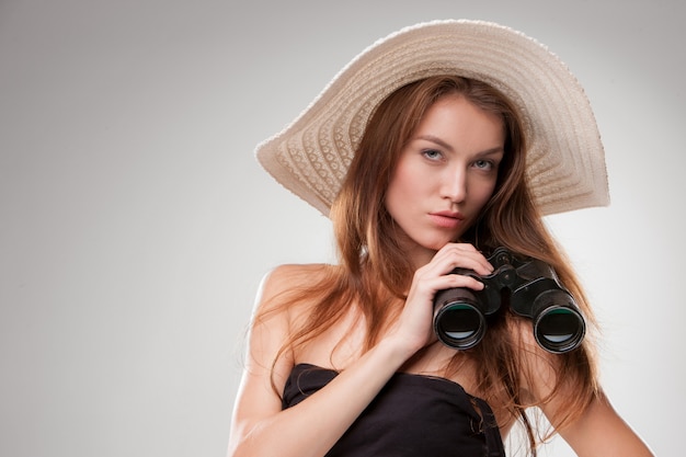 Junge Frau im Hut mit Fernglas