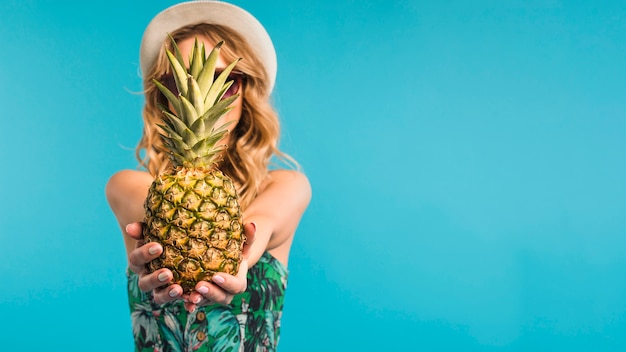 Kostenloses Foto junge frau im hut und in sonnenbrille, die ananas hält