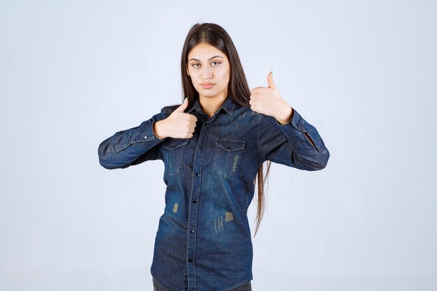 Junge Frau im Jeanshemd, das Genusszeichen zeigt