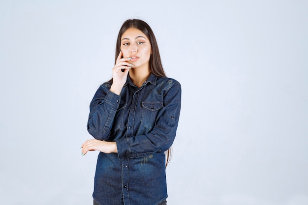 Junge Frau im Jeanshemd, die neutrale und verführerische Posen ohne Reaktionen gibt