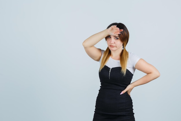 Kostenloses Foto junge frau im kleid, die hand auf die stirn hält und erschöpft aussieht