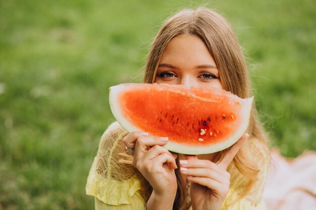 Junge Frau im Park, die Wassermelone isst