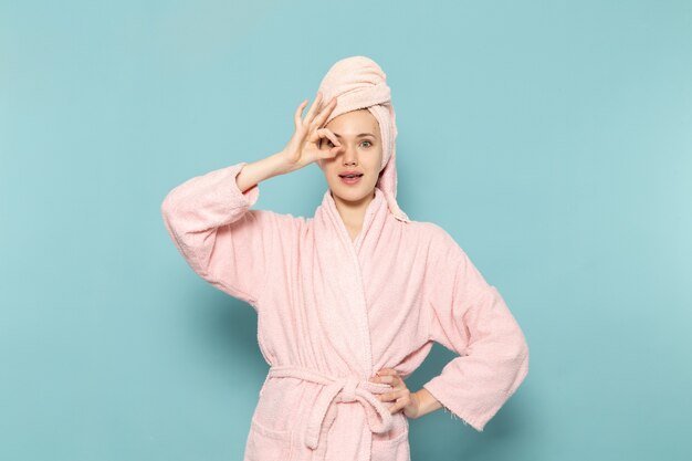junge Frau im rosa Bademantel nach der Dusche kühl posiert auf blau