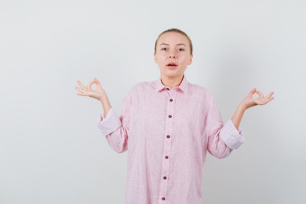 Junge Frau im rosa Hemd, das Meditation tut