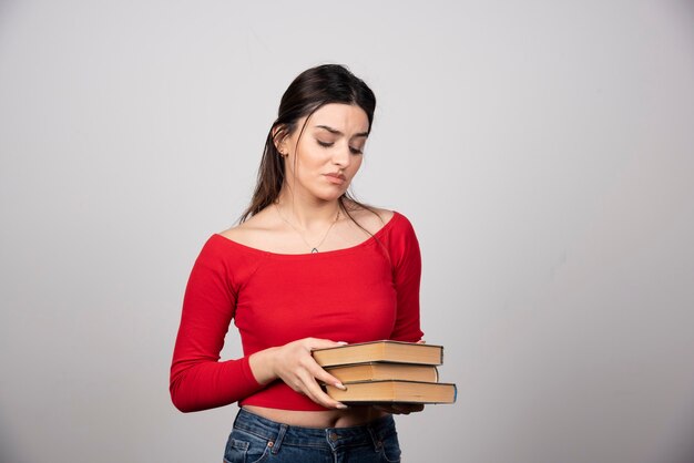 junge Frau im roten T-Shirt mit Blick auf ein Buchcover.