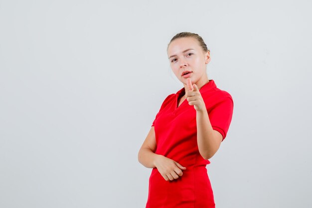 Junge Frau im roten T-Shirt zeigt und schaut selbstbewusst