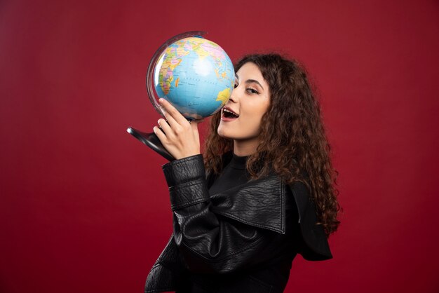 Junge Frau im schwarzen Outfit, das einen Globus hält.