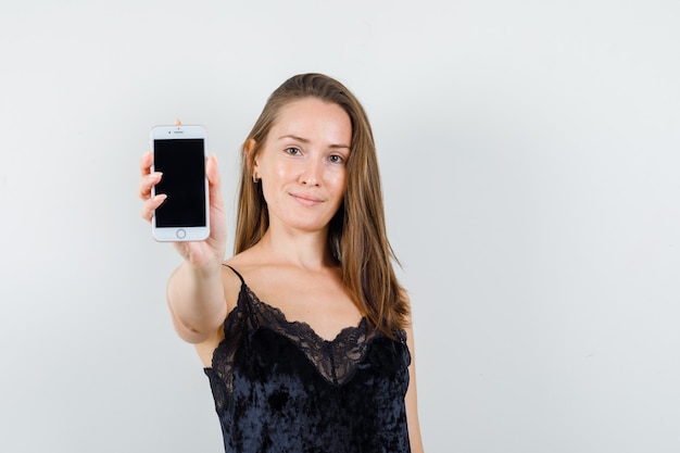 Junge Frau im schwarzen Unterhemd, das Handy zeigt und erfreut schaut