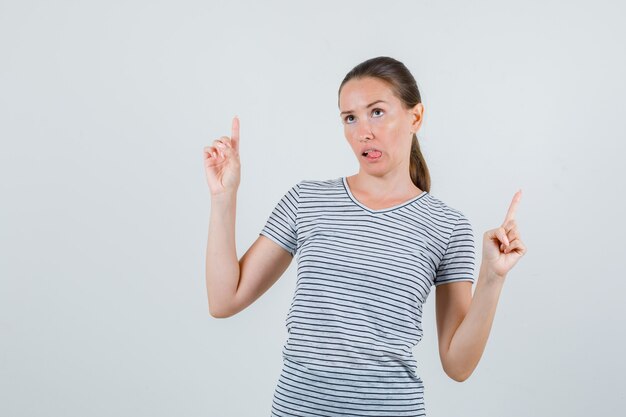 Junge Frau im T-Shirt, das oben zeigt und Zunge zeigt, Vorderansicht.