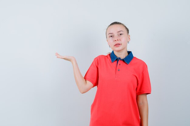 Junge Frau im T-Shirt, die vorgibt, etwas auf ihrer Handfläche zu halten