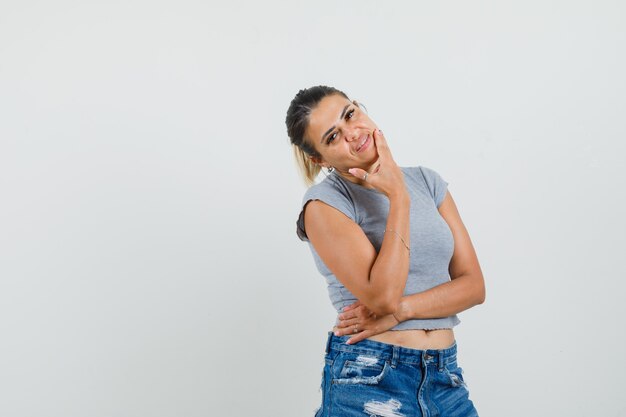 Junge Frau im T-Shirt, kurze Hosen, die im Stehen aufwerfen und elegant schauen