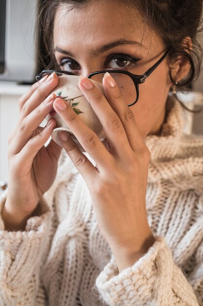 Junge Frau im trinkenden Tee des Pullovers