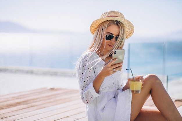 Junge Frau im Urlaub am Pool mit Telefon