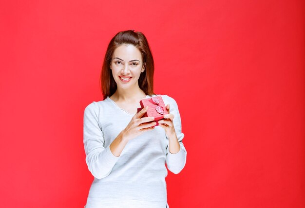 Junge Frau im weißen Hemd mit einer kleinen roten Geschenkbox