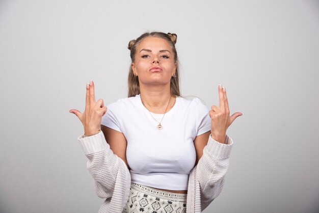 Junge Frau im weißen Outfit, das auf grauem Hintergrund steht.