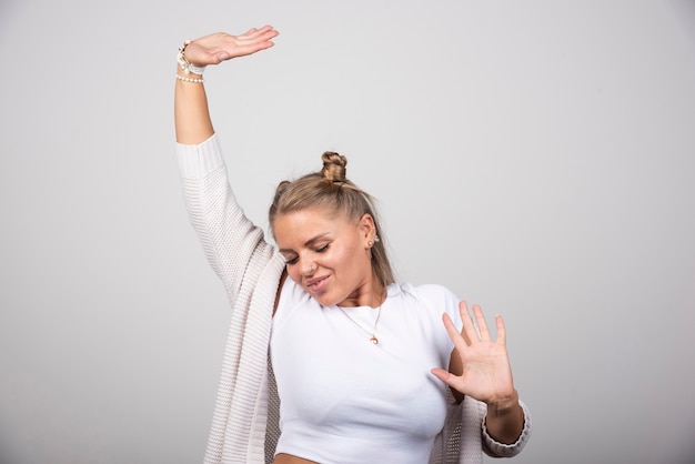 Junge Frau im weißen Outfit, das glücklich tanzt.