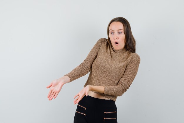 Junge Frau in Bluse, Rock, der etwas am Boden zeigt und verblüfft aussieht, Vorderansicht.