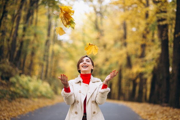 Junge Frau in den werfenden Blättern eines Herbstparks