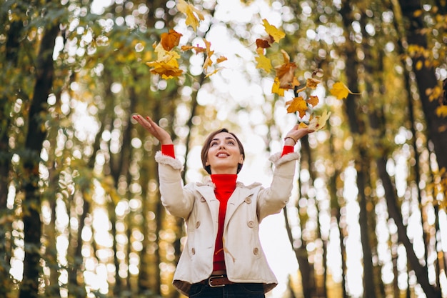 Junge Frau in den werfenden Blättern eines Herbstparks