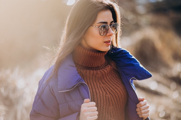 Junge frau in der blauen jacke draußen im park